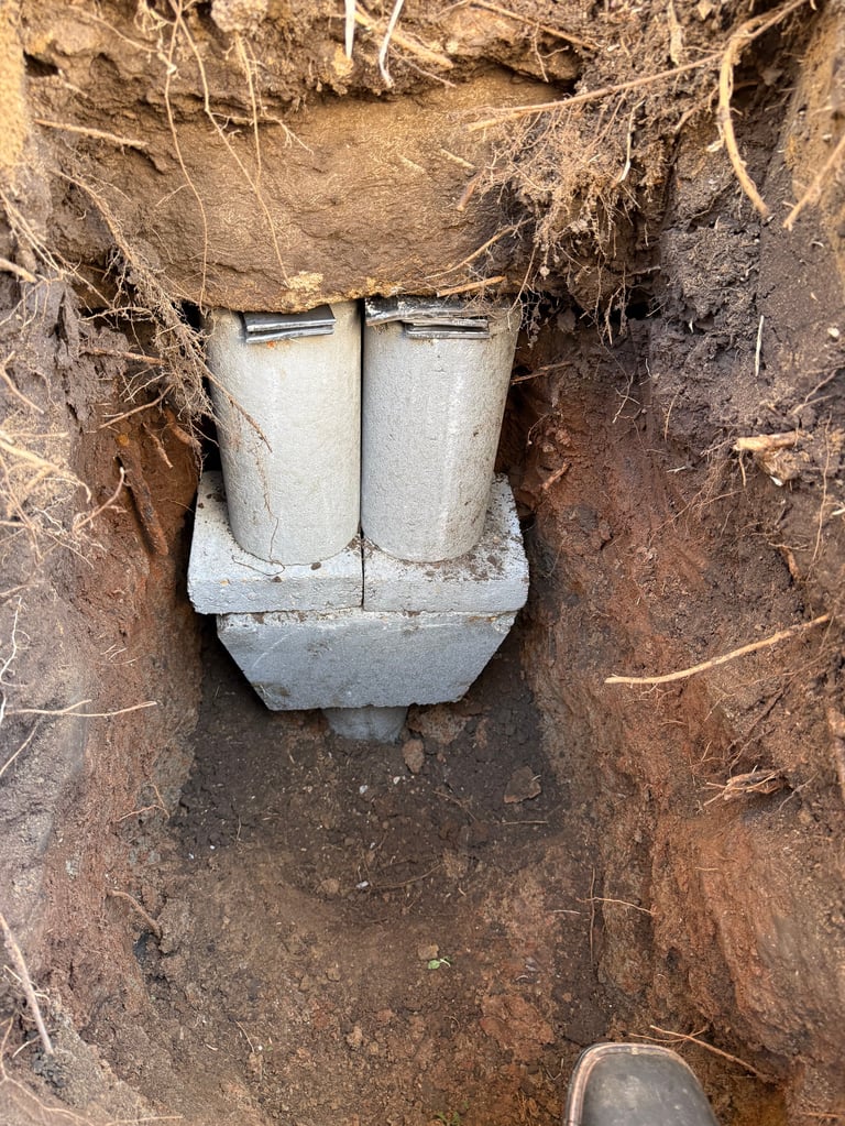 Underground septic tank system with two cylindrical concrete pipes and collection basin surrounded by soil and roots